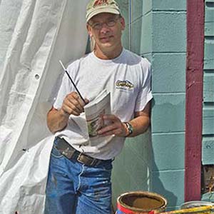 Man painting near colorful container.