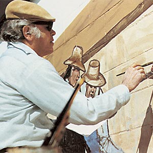 Artist painting mural with figures.