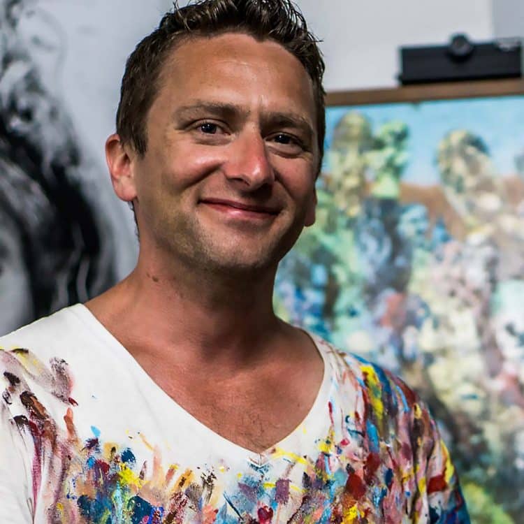Artist in colorful paint-stained shirt.
