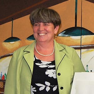 Woman in green jacket with pearls.