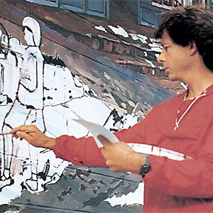 Artist painting mural on wall.