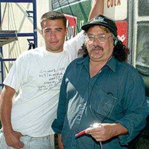 Two men posing in front of mural.
