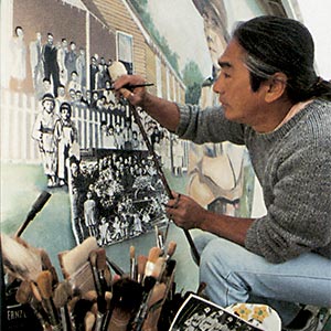 Artist painting mural with brushes.
