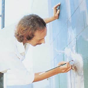 Person painting a wall outdoors.