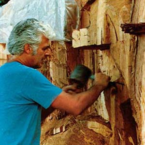Man carving wood with tools.