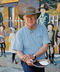 Artist holding palette in front mural.