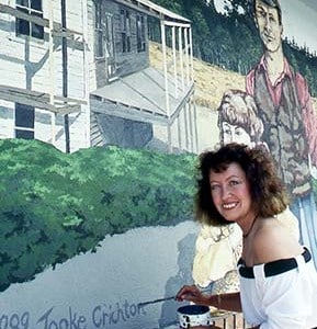 Artist painting a mural outdoors.