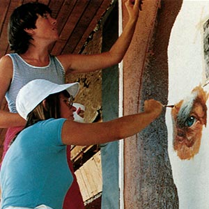 Two women painting a mural.